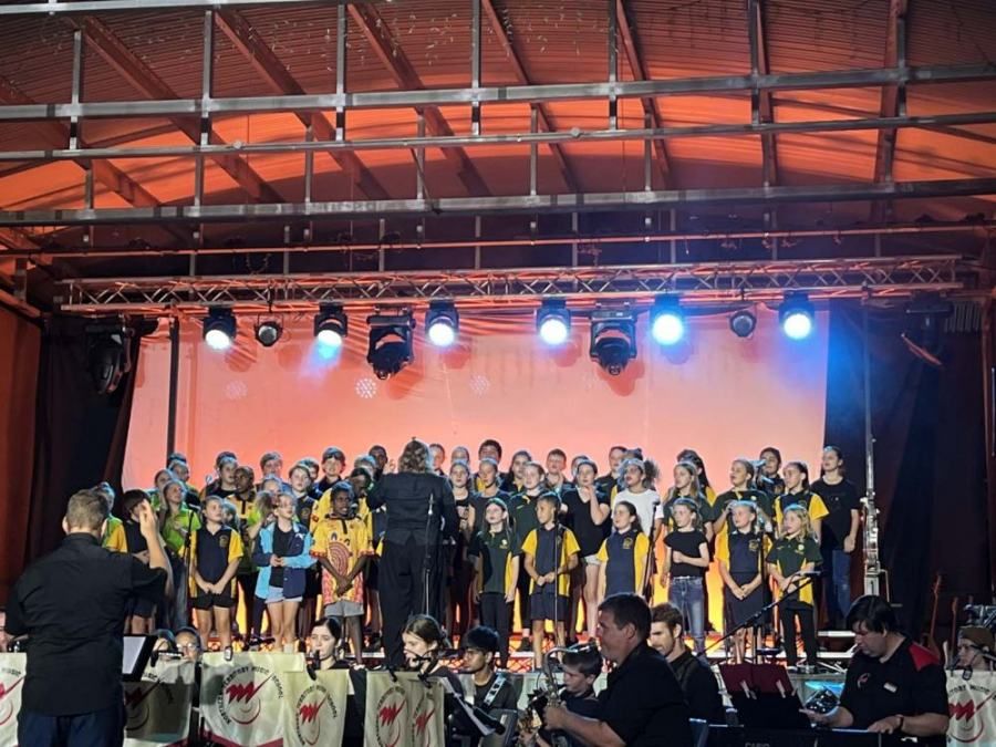 A choir is performing on a stage with a conductor