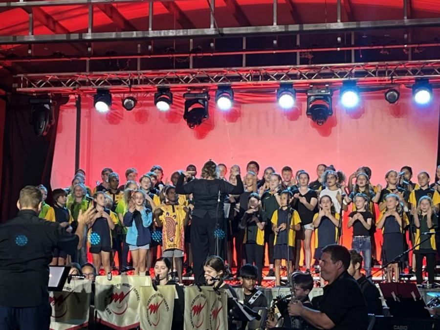A large group of children are singing on a stage.