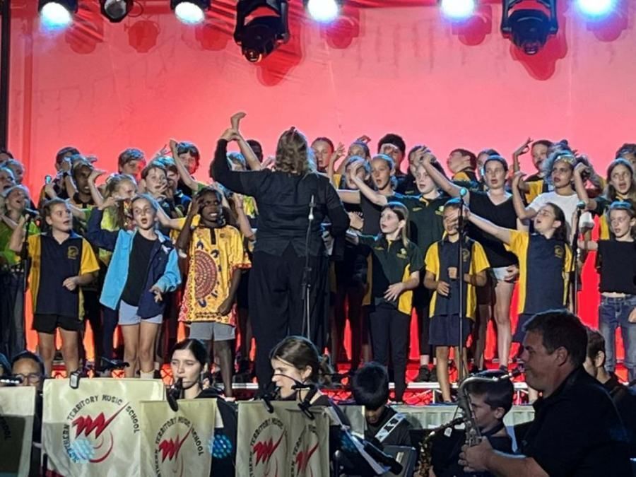 A large group of children are singing on a stage