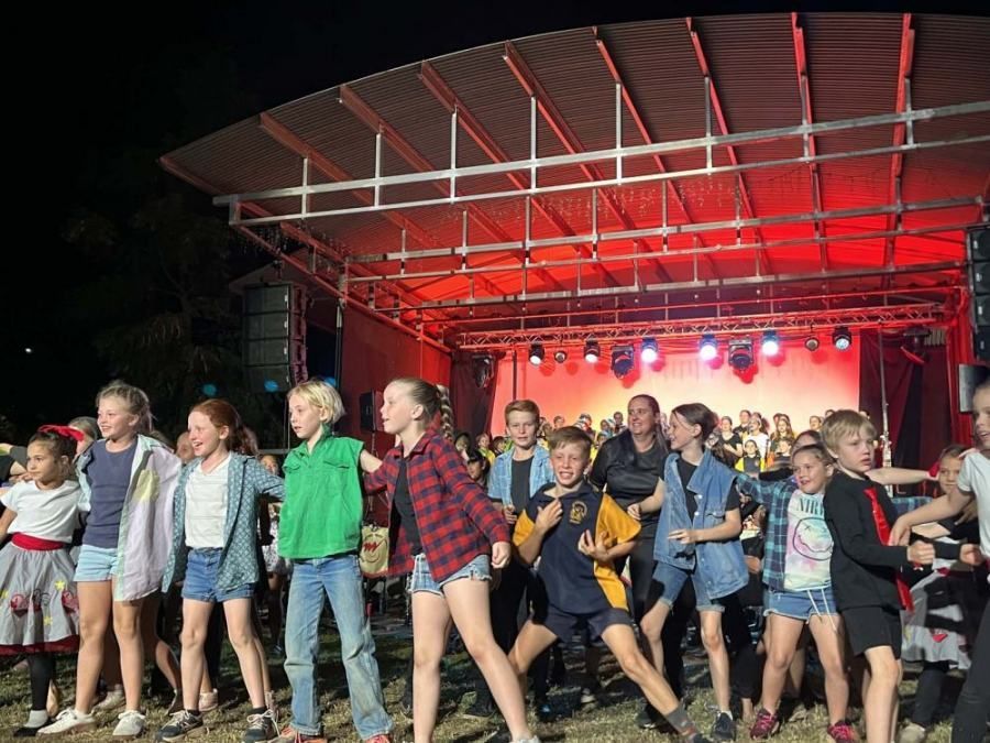 A group of children are dancing on a stage at night.