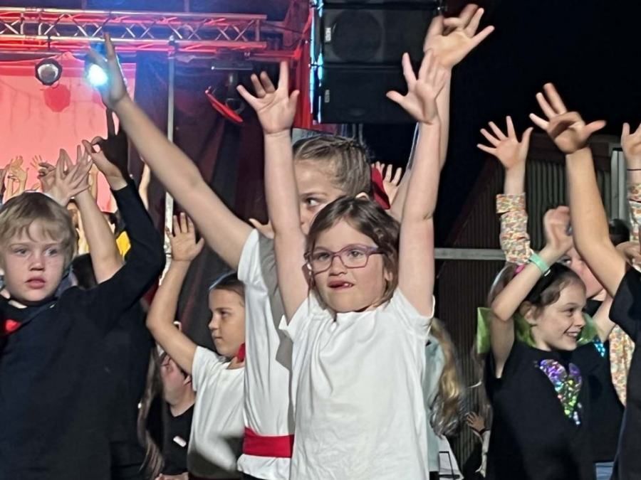 A group of children are dancing with their hands in the air