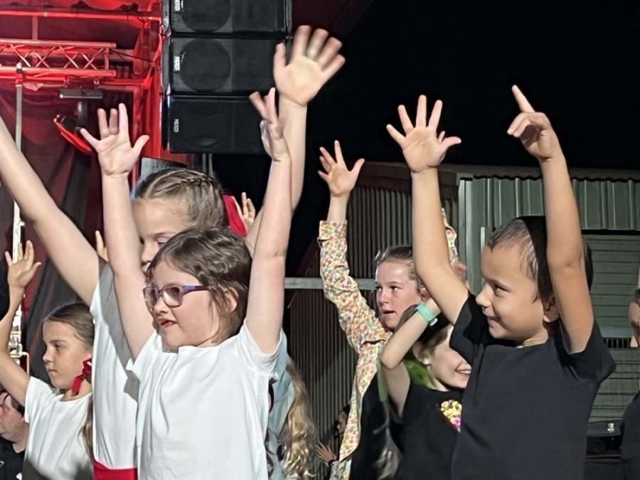 A group of young girls are raising their hands in the air