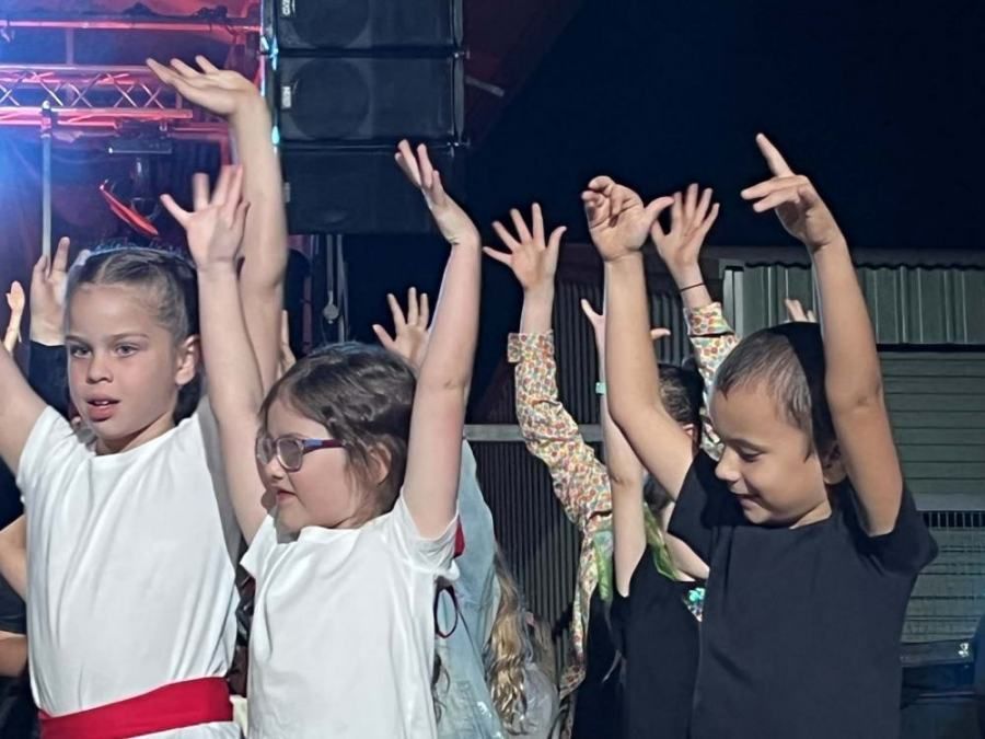 A group of children are dancing with their hands in the air