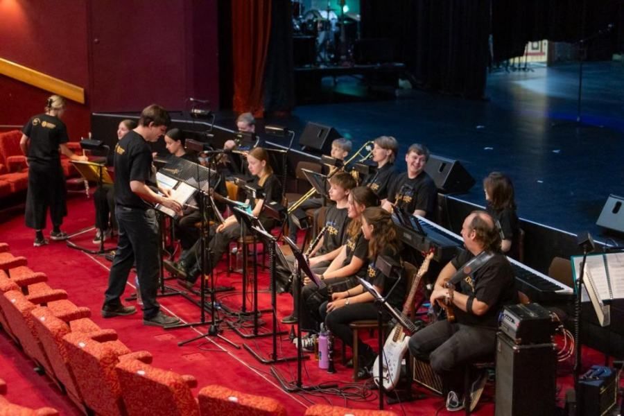 A group of people are playing instruments on a stage in a theater.
