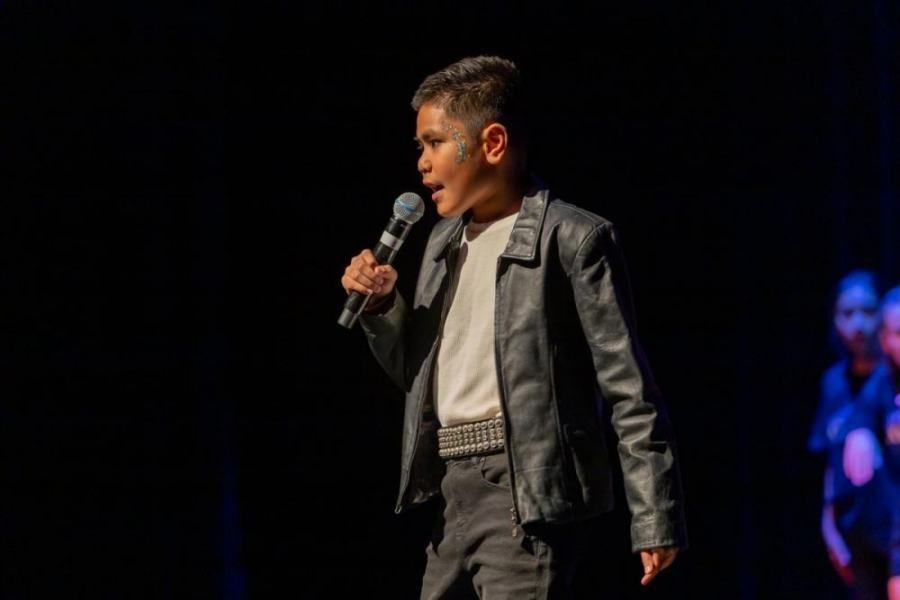 A young boy is singing into a microphone on a stage.