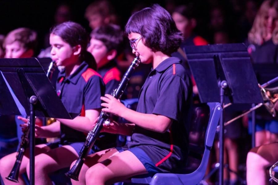 A girl is playing a clarinet in an orchestra.