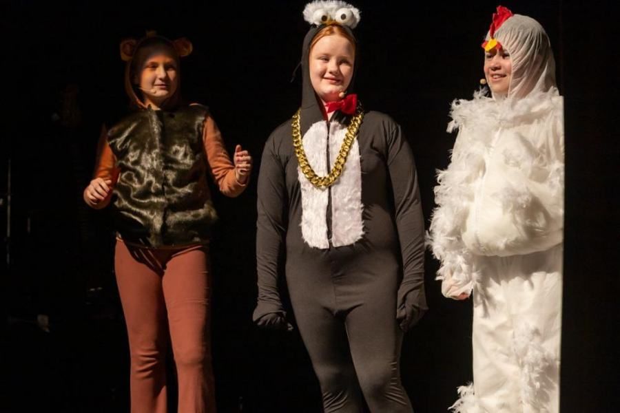 Three children in animal costumes are standing next to each other on a stage.