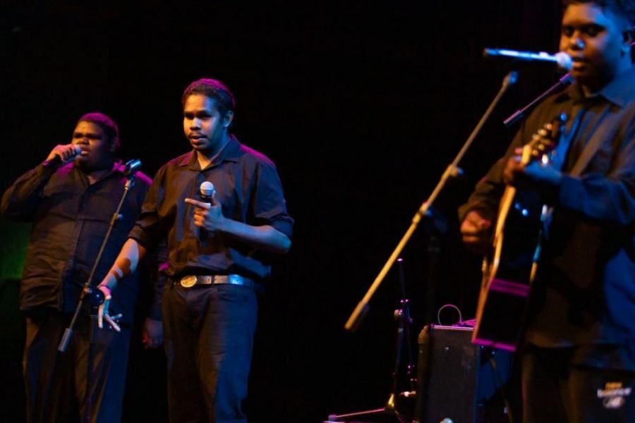 A group of men are singing into microphones on a stage.