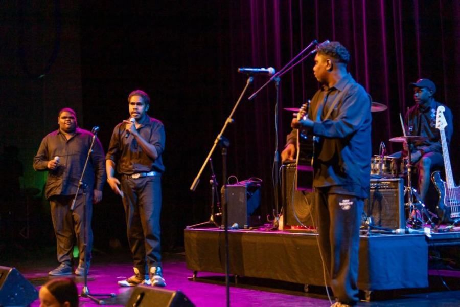 A group of men are singing into microphones on a stage.