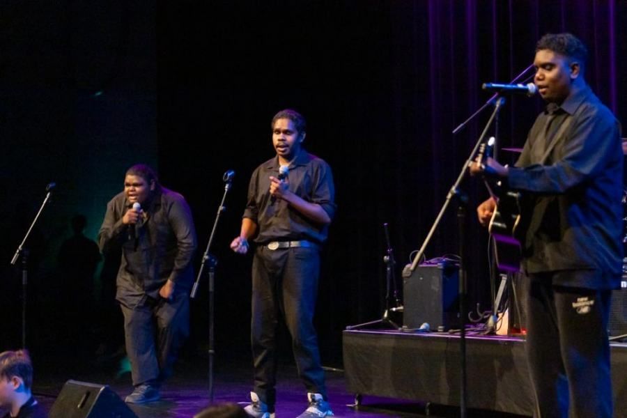 A group of men are singing and playing instruments on a stage.