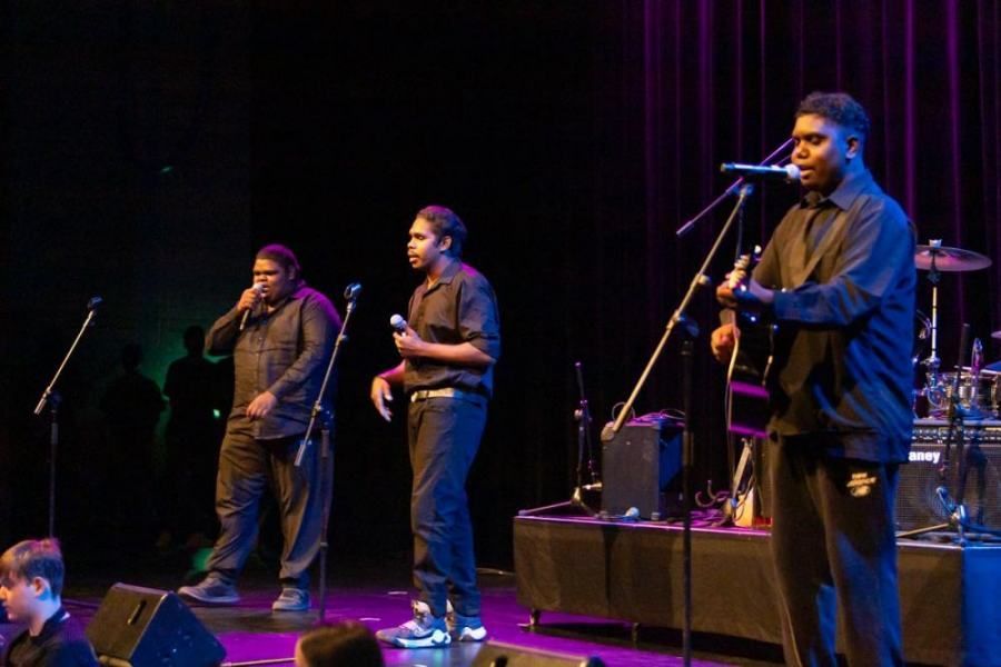 A group of men singing into microphones on a stage