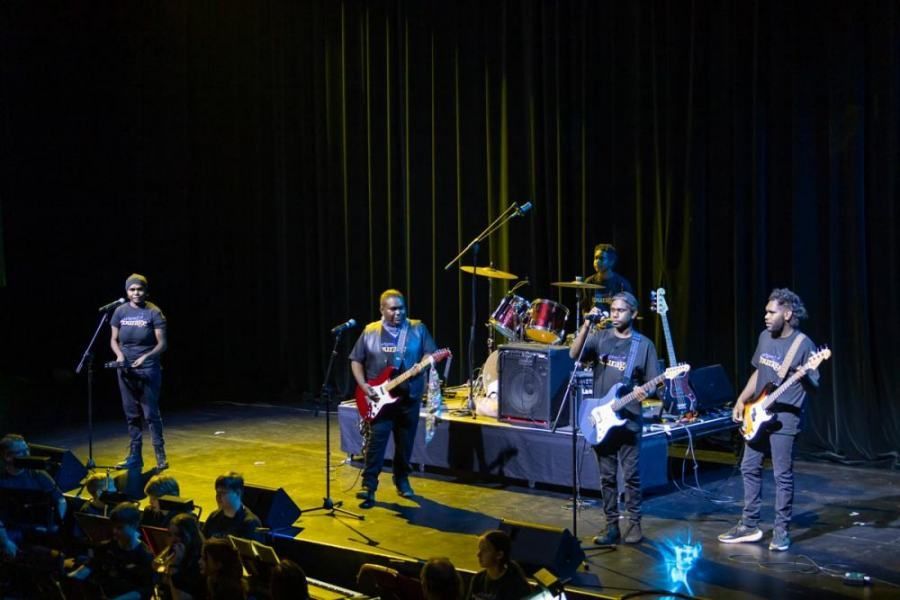 A group of people are playing guitars on a stage in front of a crowd.