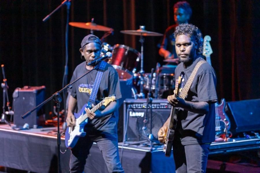 Two men are playing guitars on a stage in front of a laney amplifier.