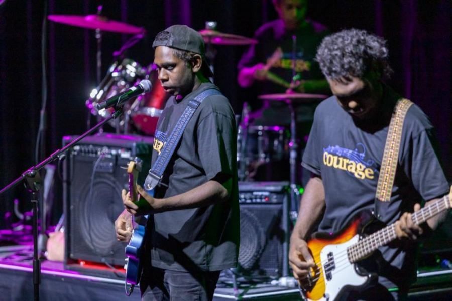 Two men are playing guitars on a stage.