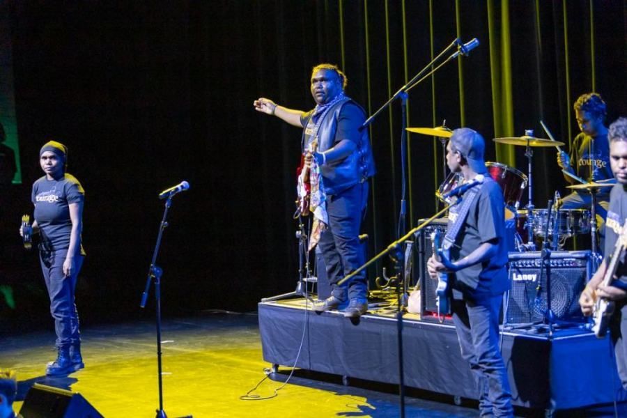 A group of people are standing on a stage playing instruments.