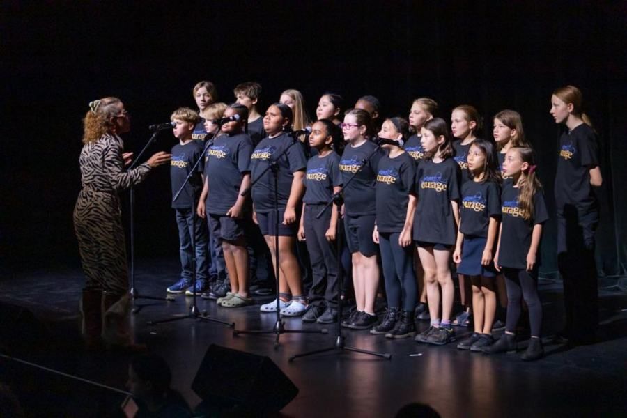 A group of children are singing into microphones on a stage.