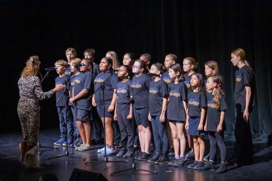A group of children are singing on a stage in front of a microphone.