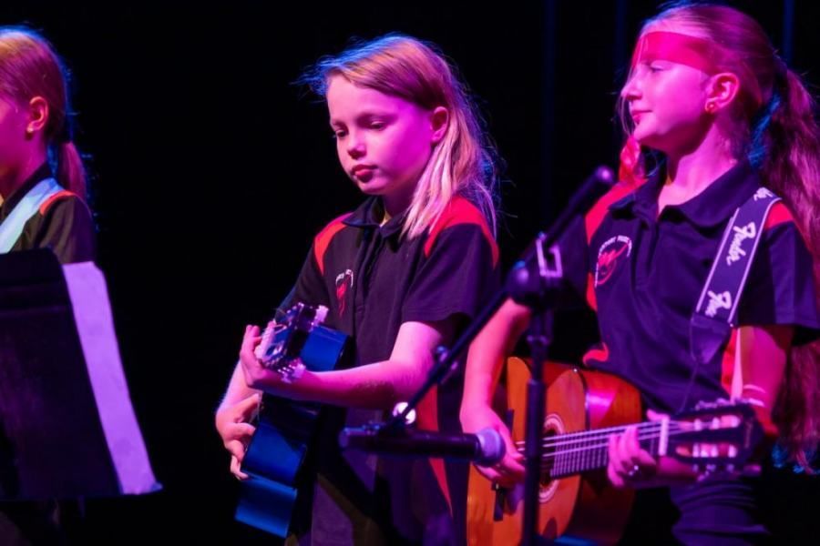 A group of young girls are playing guitars on a stage.