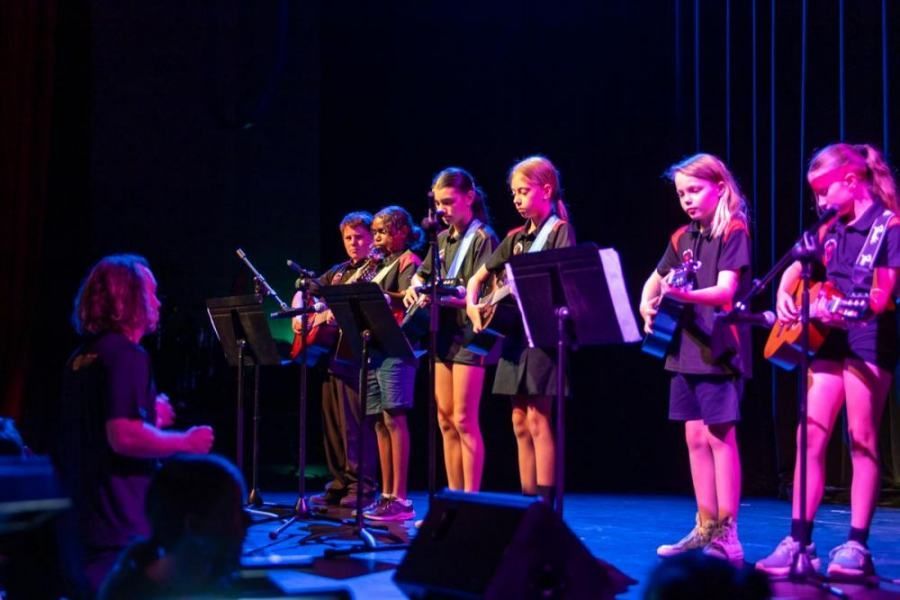 A group of young girls are playing guitars on a stage.