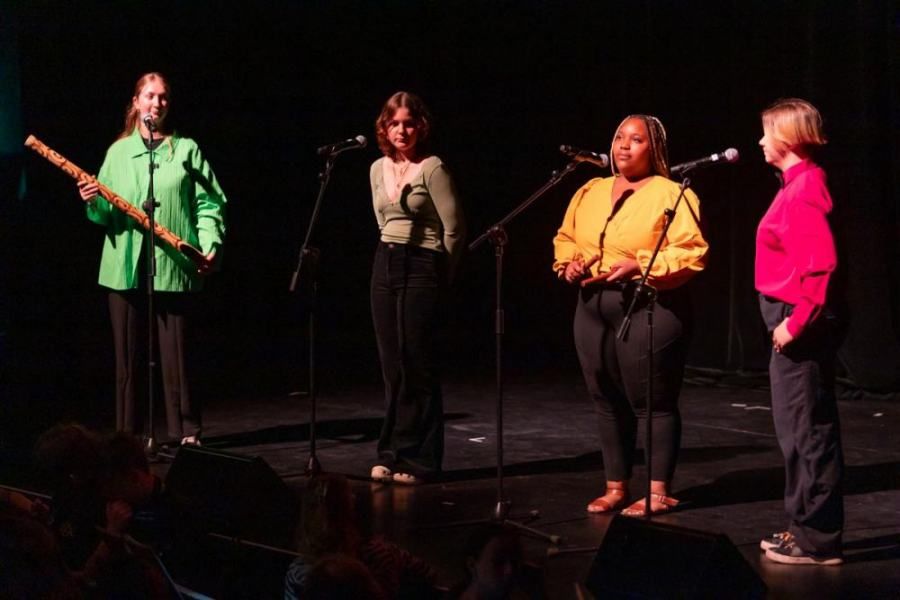 A group of women are singing into microphones on a stage.