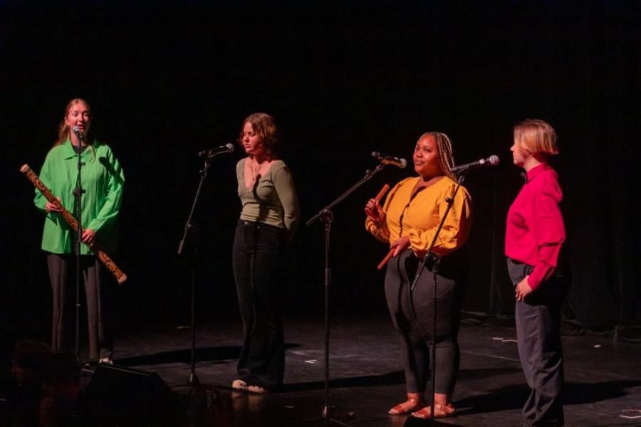 A group of women are singing into microphones on a stage.