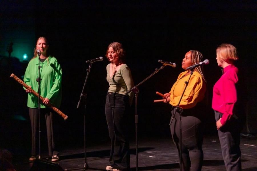 A group of women are singing into microphones on a stage.