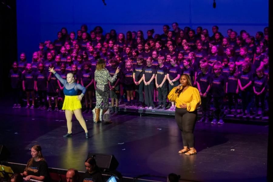 A group of people are standing on a stage in front of a large choir.