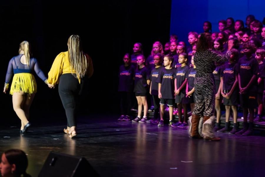 A group of people are standing on a stage holding hands.