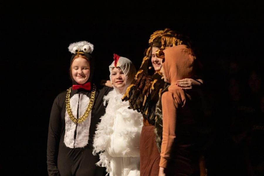 A group of children dressed in costumes are standing next to each other on a stage.