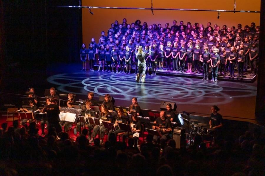 A large choir and orchestra are performing on a stage.
