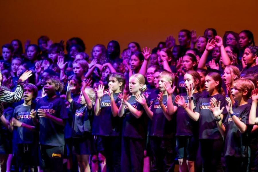 A large group of children are singing on a stage.