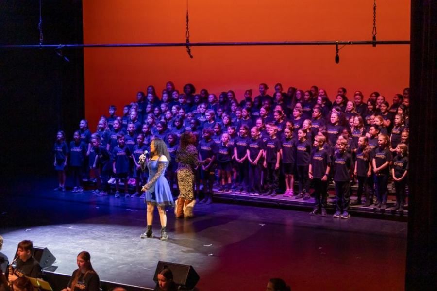 A group of people are standing on a stage in front of a large choir.