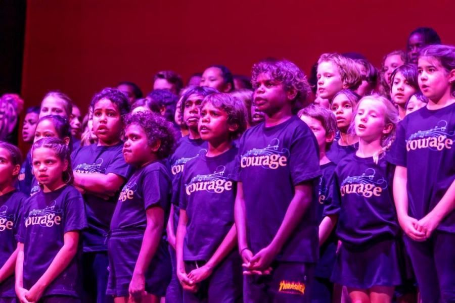 A group of children wearing purple shirts that say courage