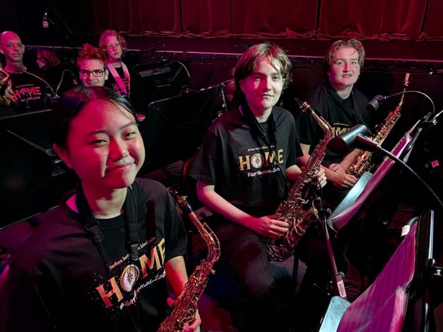 A group of people are playing saxophones in a band.