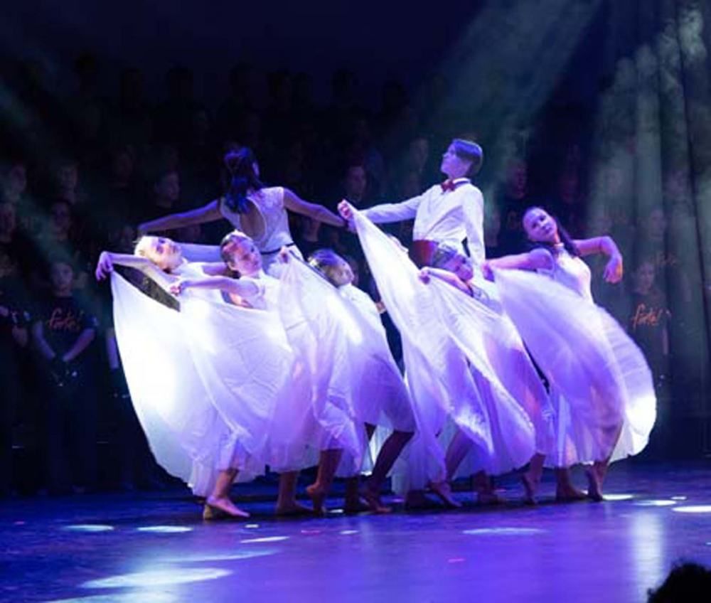 A group of dancers are dancing on a stage in front of a crowd.