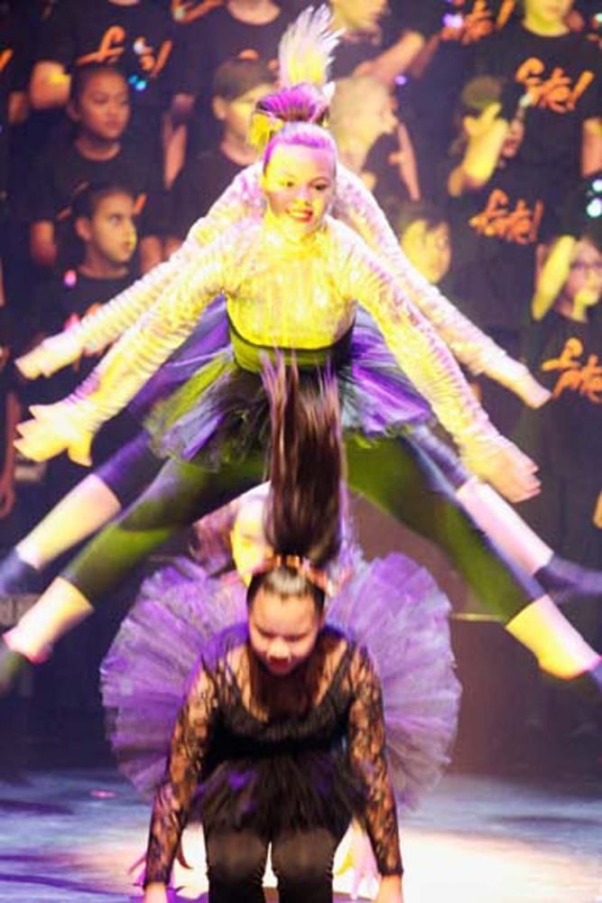 A group of dancers are performing on a stage in front of a crowd.