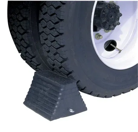 Black rubber wheel chock in front of a truck tire, preventing movement.