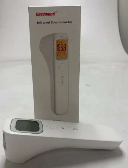 White infrared thermometer and its box, displaying a digital temperature reading.