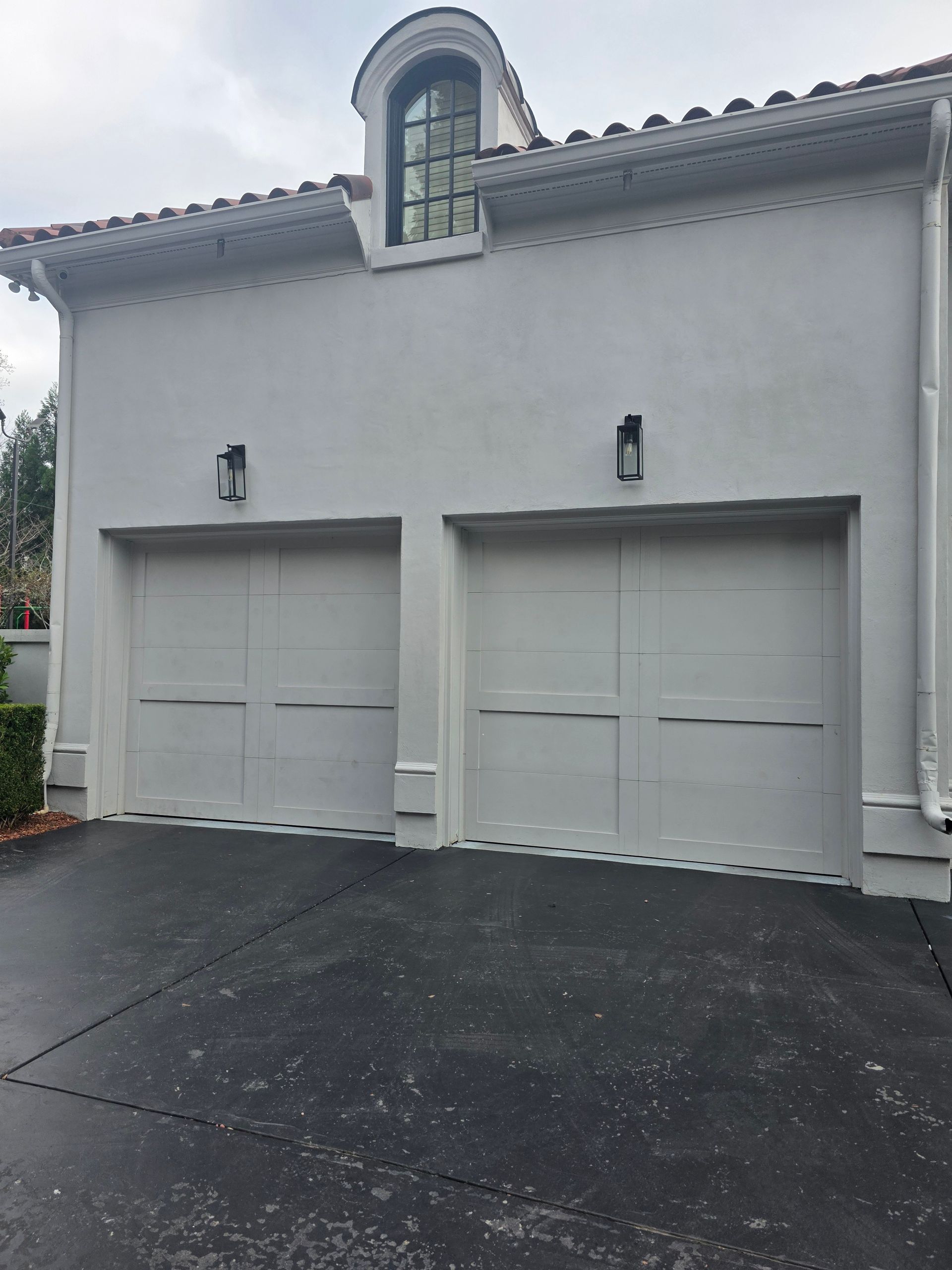 Inside a bright, empty garage with a closed white door and gray flooring.