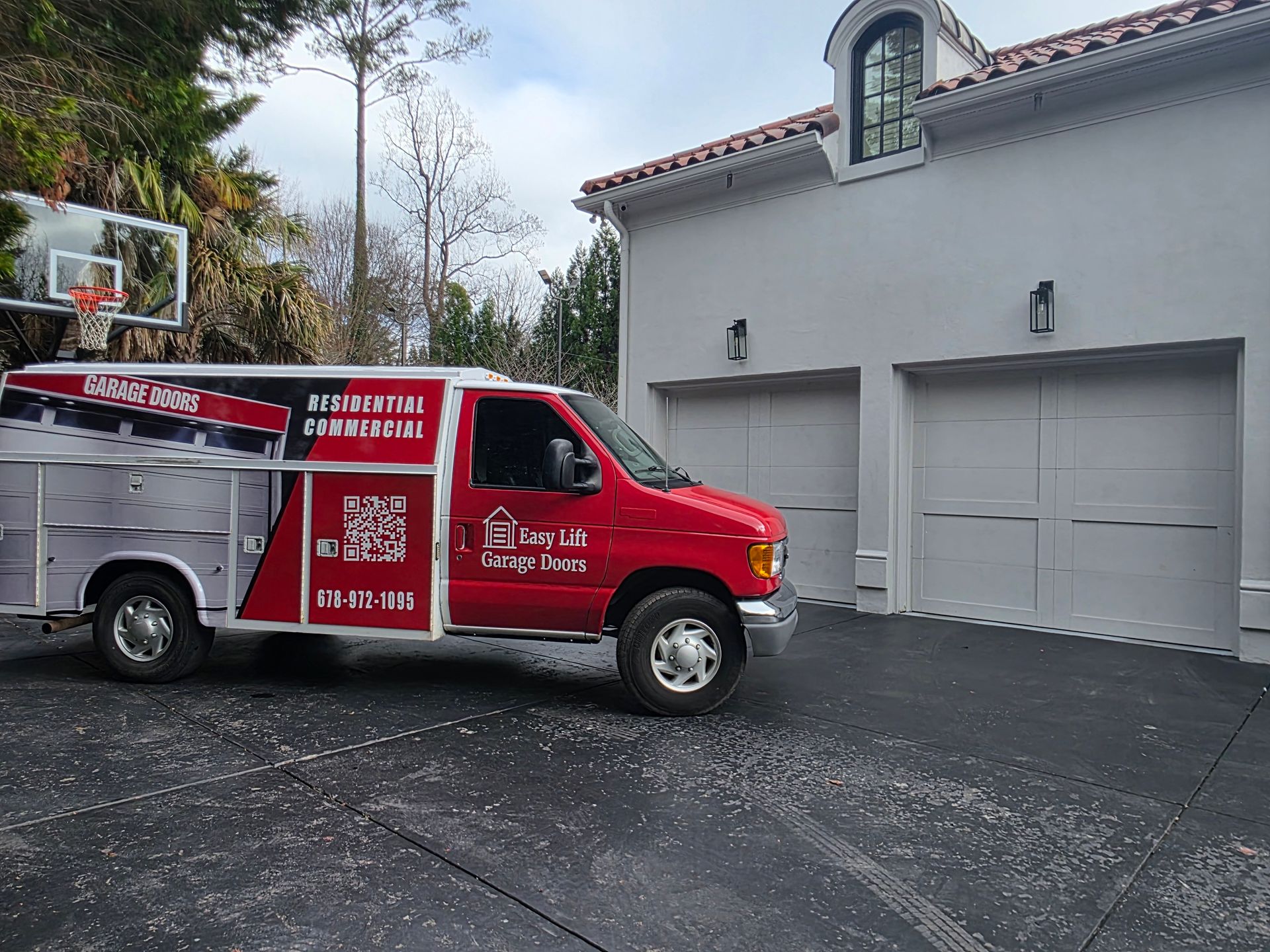 Brick building with three garage doors. Brown doors, yellow bollards, blue sky.