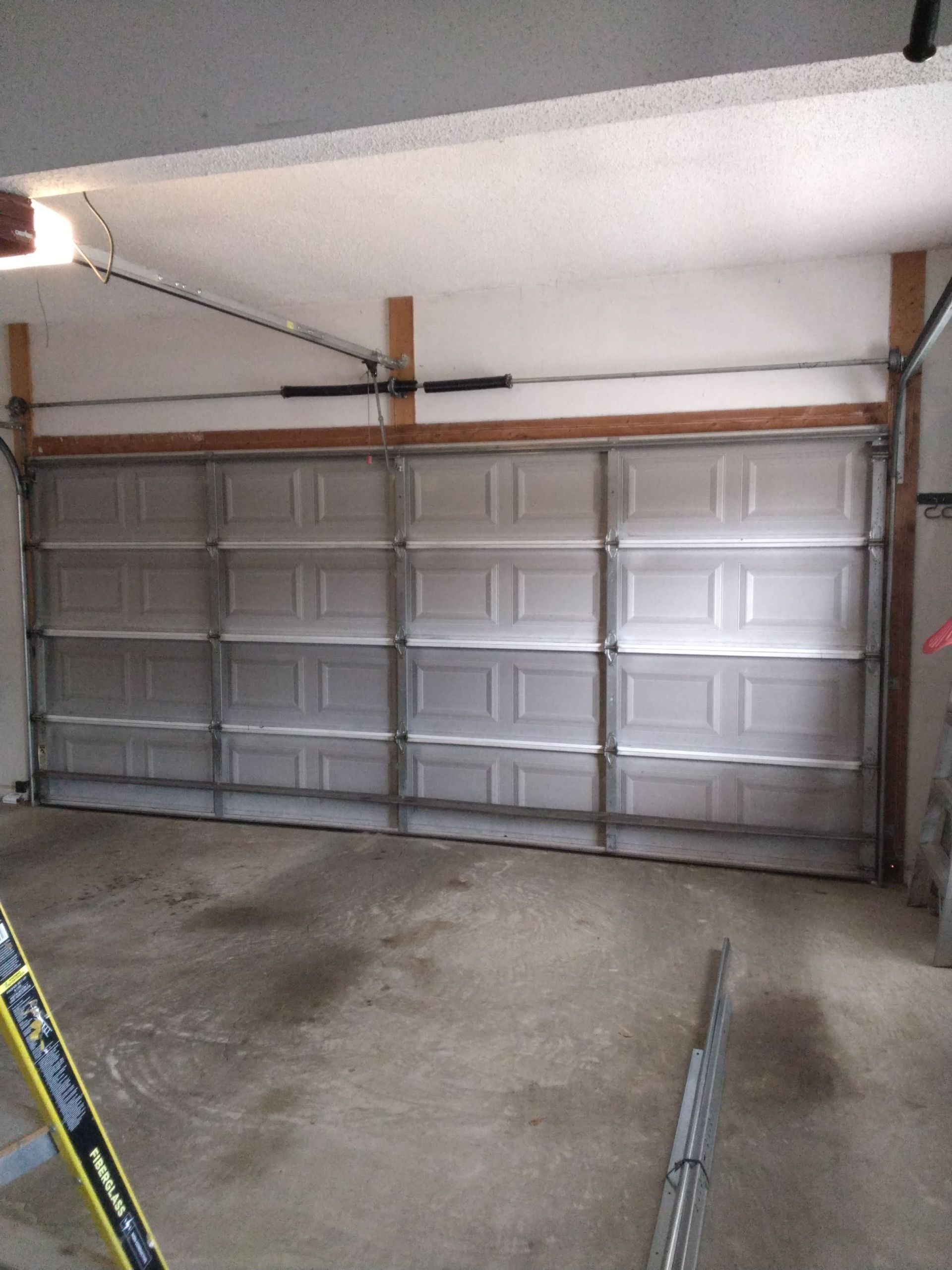 Tan garage doors with window panes, one next to stone facade.