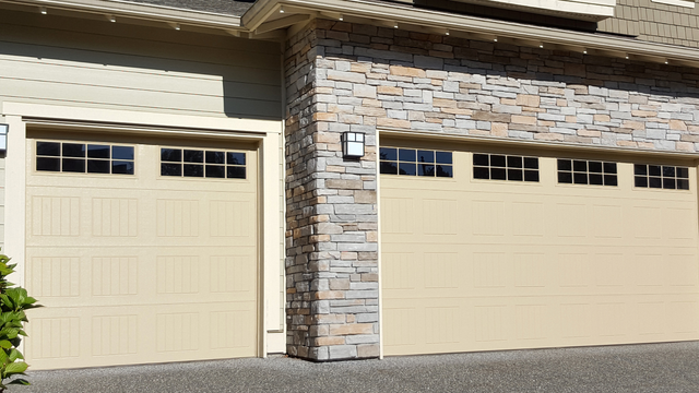 Tan garage doors with window panes, one next to stone facade.