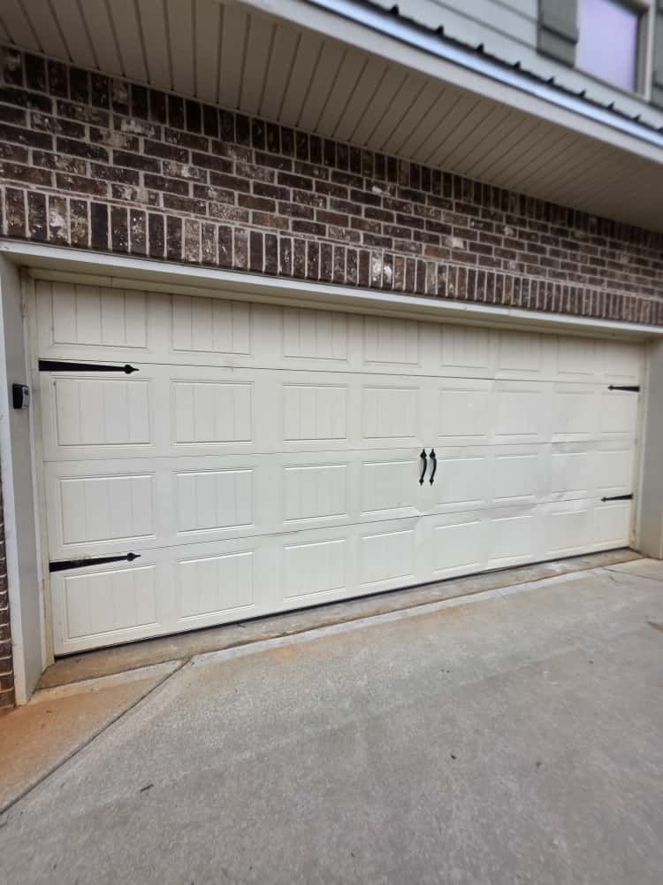 Row of houses with attached garages on a sunny street, blue sky above.