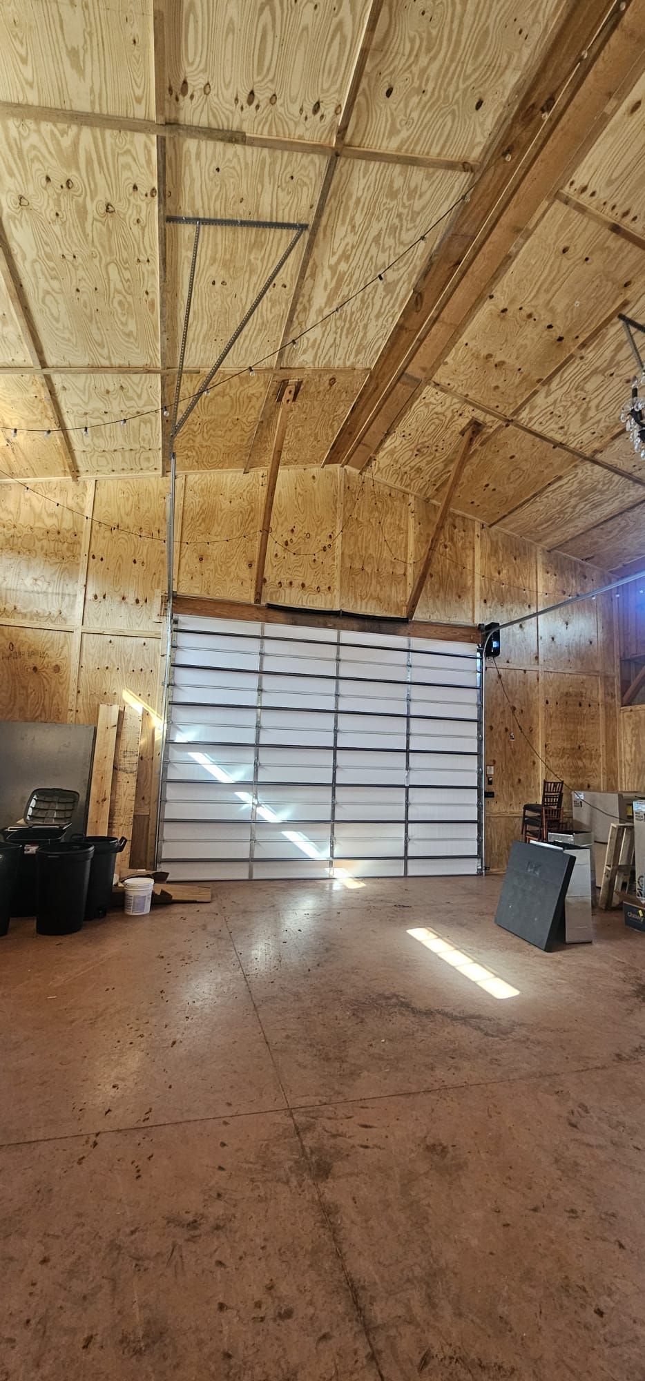 Three white garage doors in a row, with a red-tiled roof above, fronted by a hedge.