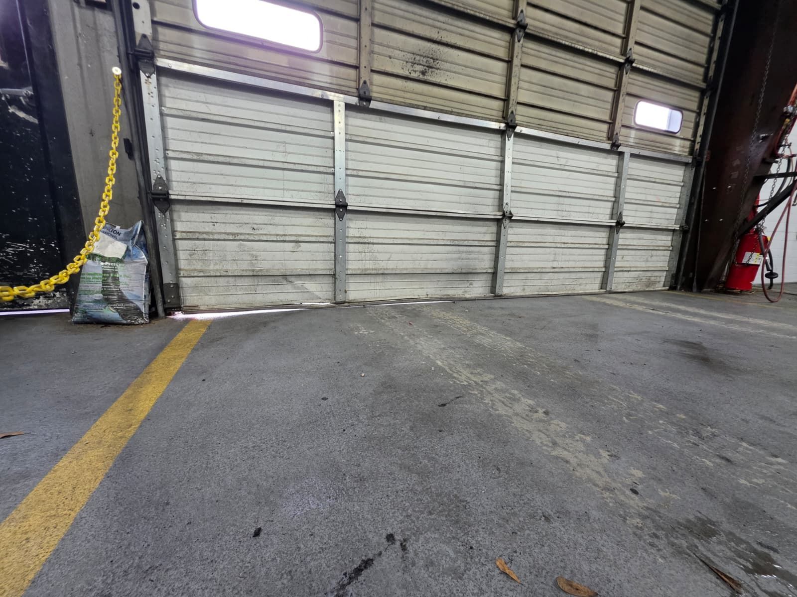 Row of yellow industrial doors on a warehouse with a gray exterior, on a brick paved surface.