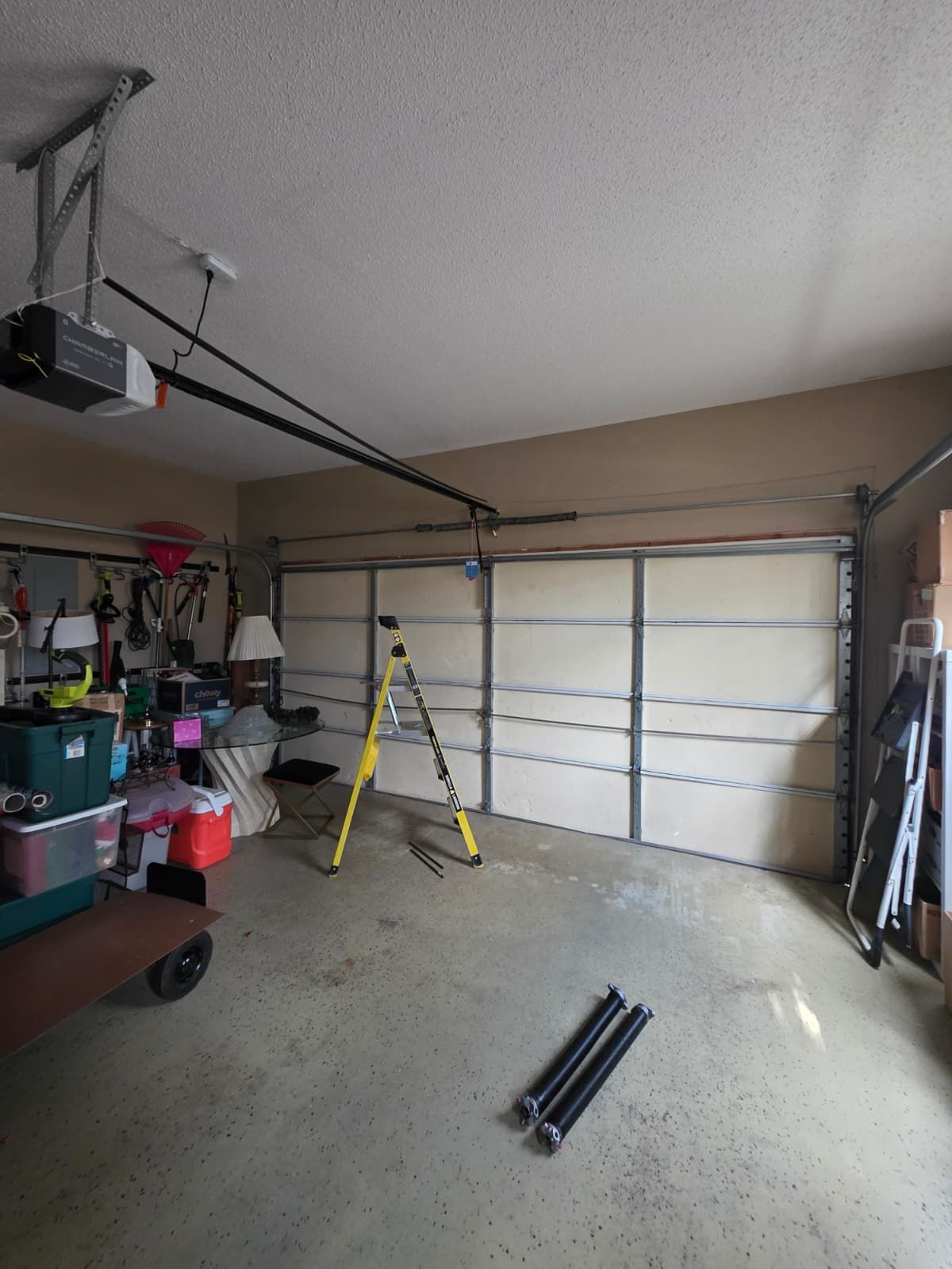 Brick building with three garage doors. Brown doors, yellow bollards, blue sky.