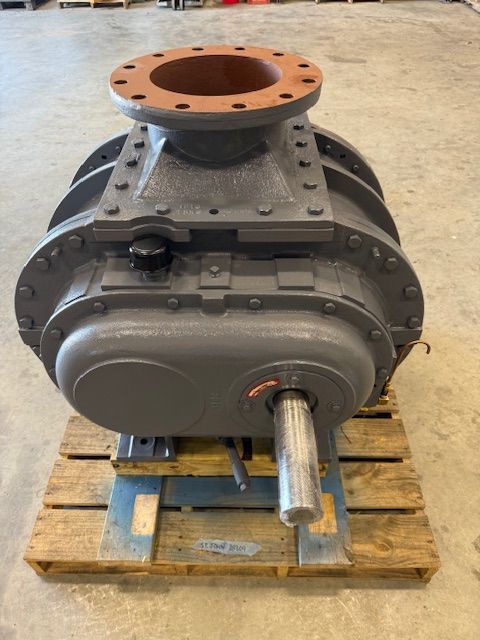Large industrial machine on a wooden pallet, with a gray housing, orange flange, and metal shaft.