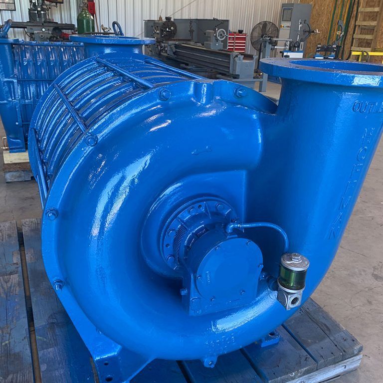 Large blue industrial blower or pump machine in a workshop on a wooden pallet