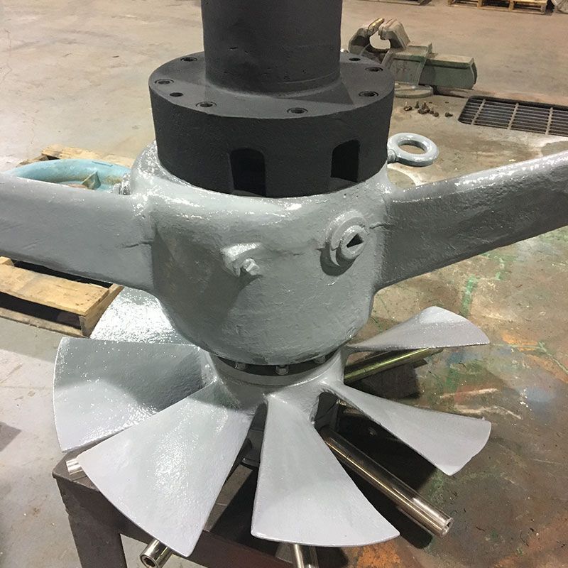 Industrial metal impeller with gray blades mounted on a shaft in a workshop.