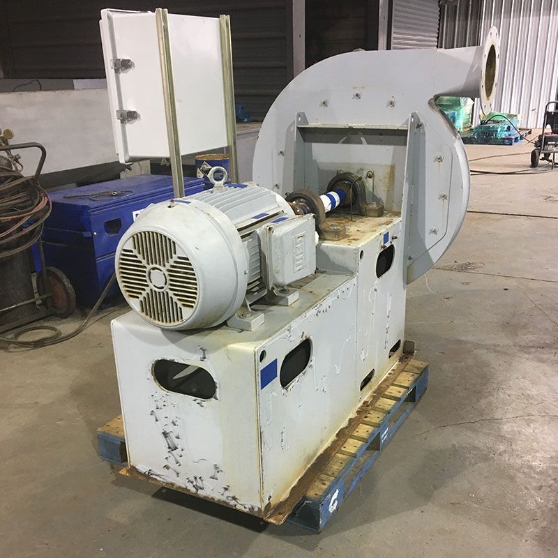 Large industrial electric motor on a pallet in a warehouse, connected to a circular machine housing.